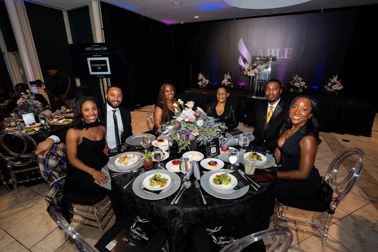 Guests seated around a dinner table in front of the stage at the ABLE Legacy Gala