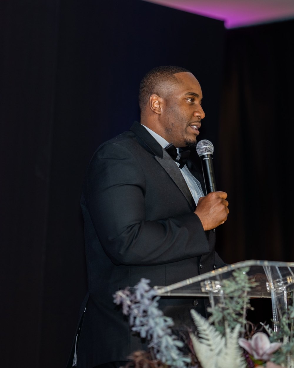 Andra Howard speaking at the ABLE Legacy Gala, microphone in hand