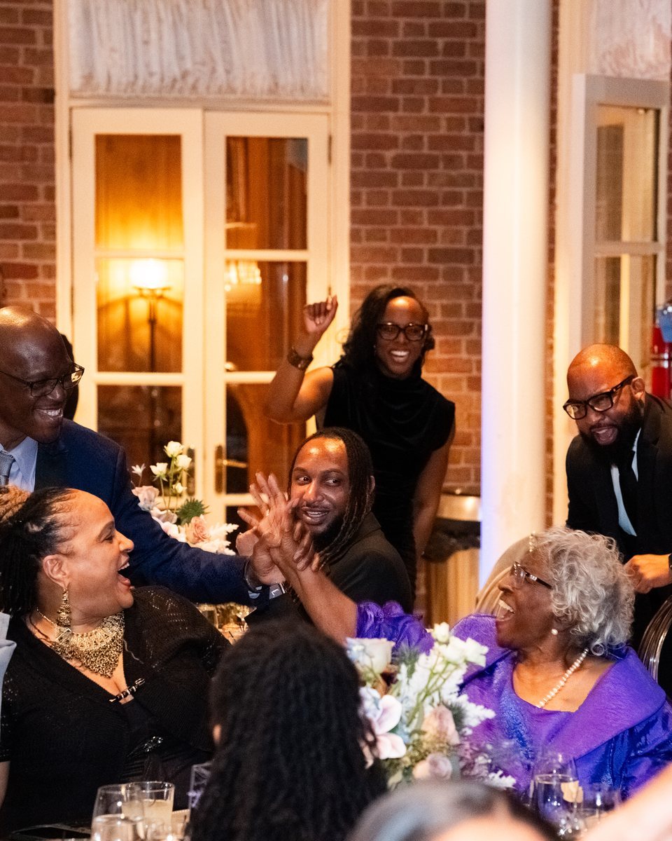 Guests laughing and cheering together around a table at the ABLE Legacy Gala