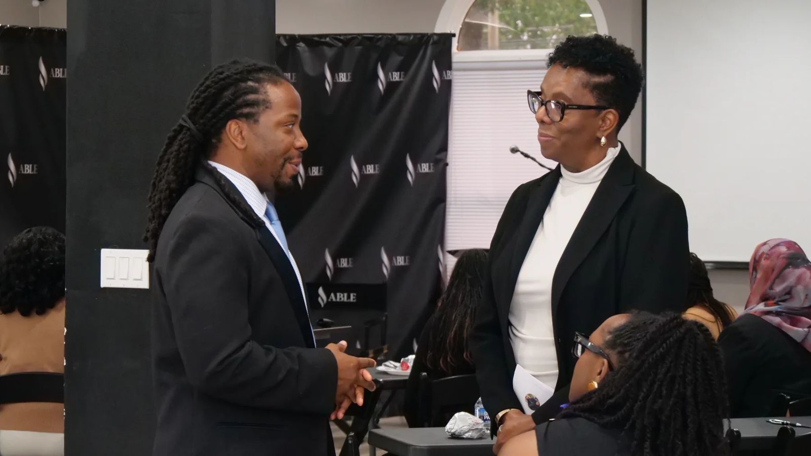 Two Leadership Lab participants deep in conversation in front of the ABLE backdrop